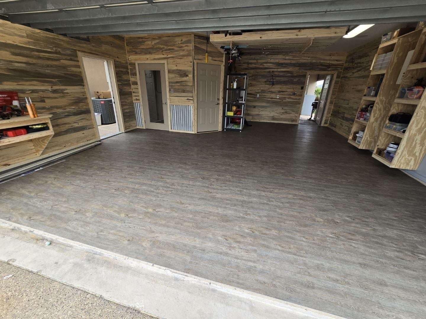 Garage after: plank flooring installed and built-in shelving stocked with tackle and tools