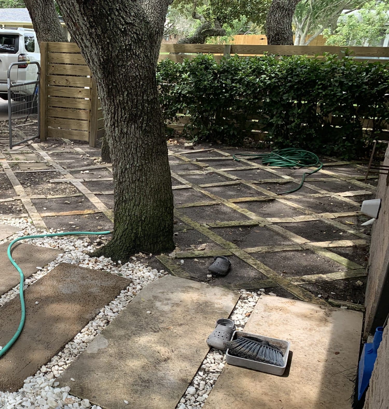 Side yard before the project: overgrown stone and gravel patio under a live oak